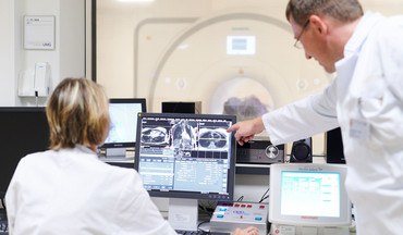 Ärzte analysierern die MRT-Aufnahmen, welche auf dem Monitor zu sehen sind.